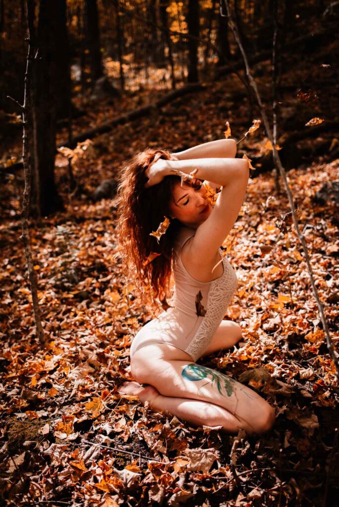 woman in the falling leaves posing for outdoor boudoir session in ottawa