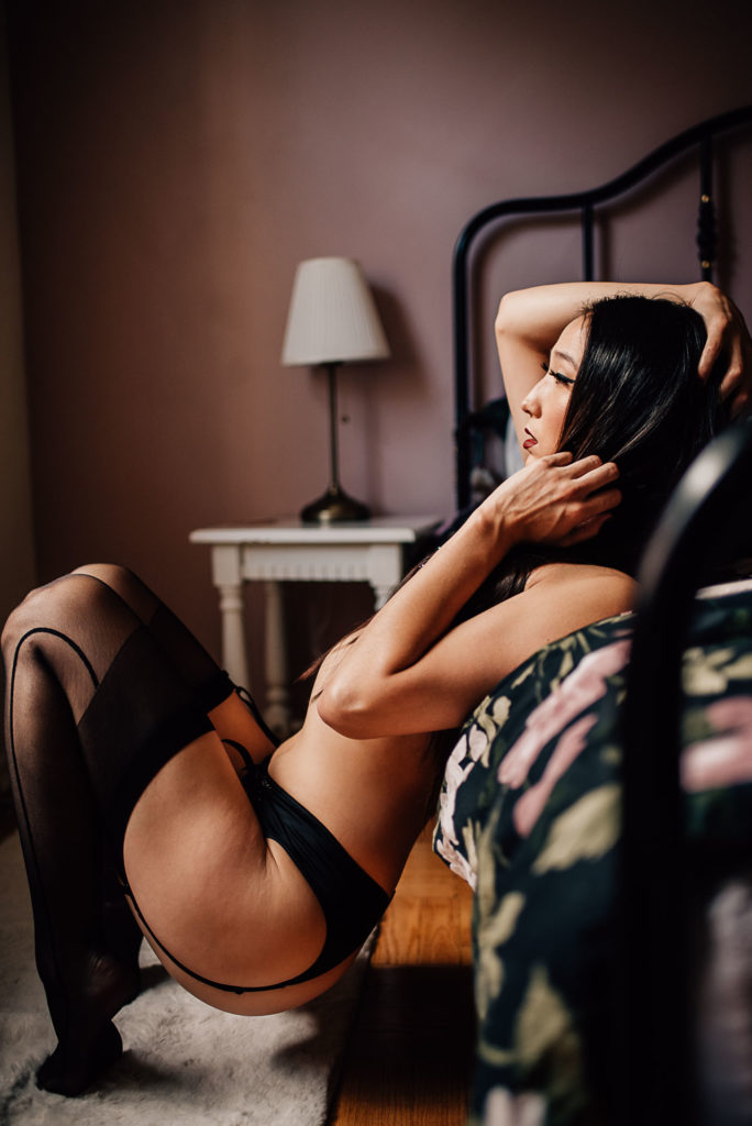 woman leaning on bed directed by her luxury boudoir photographer