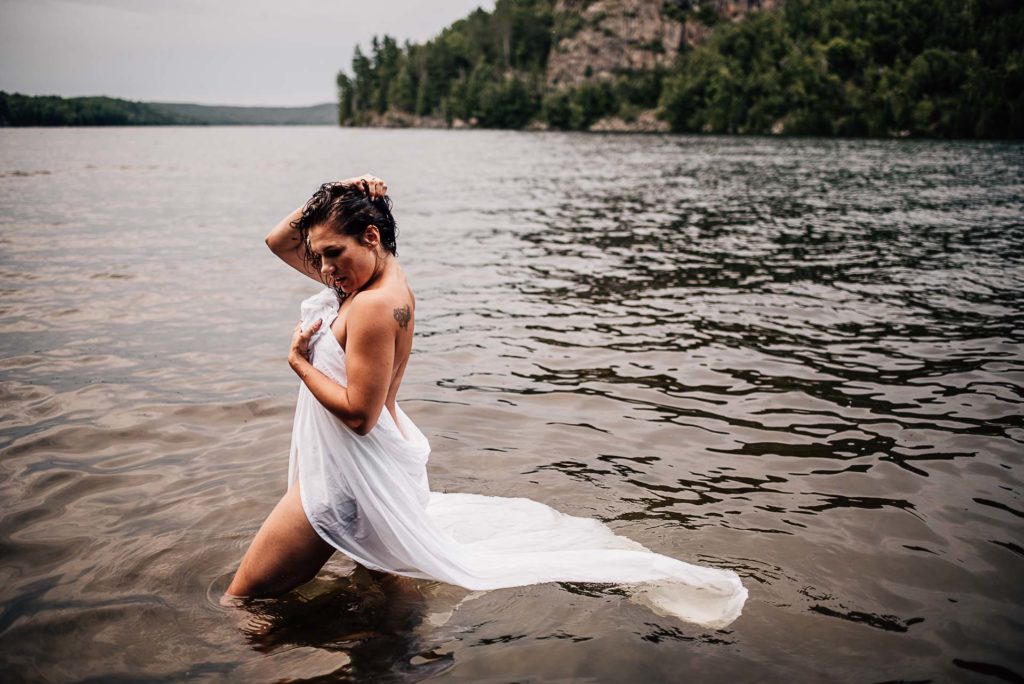 Woman posing in the lake with a sheet for outdoor boudoir photoshoot