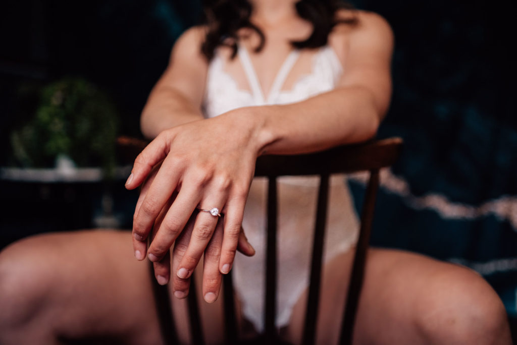 woman posing with engagement ring at boudoir photo shoot