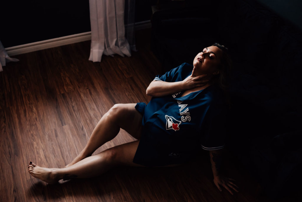 woman posing in husband's jersey for boudoir photo shoot